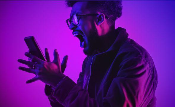 man screaming at his mobile phone studio lighting in pink and purples