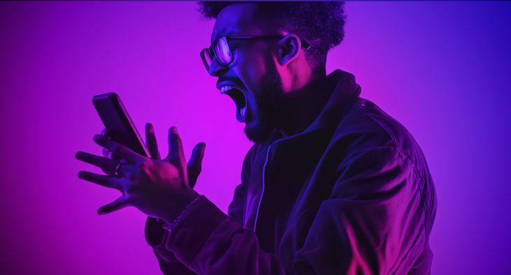 man screaming at his mobile phone studio lighting in pink and purples