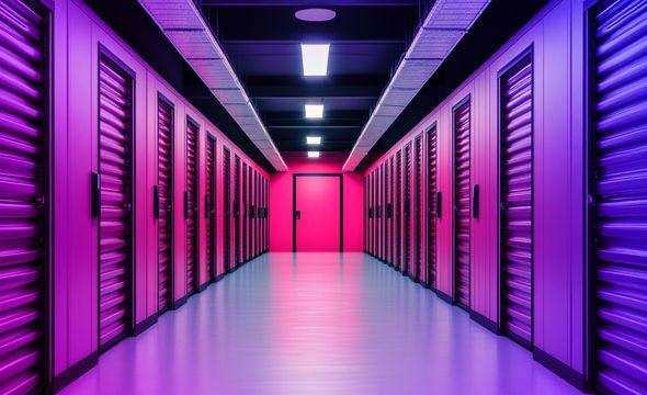 A storage unit corridor of closed doors to storage units lit by fluorescent lighting