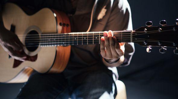 Cl;ose up of man playing guitar