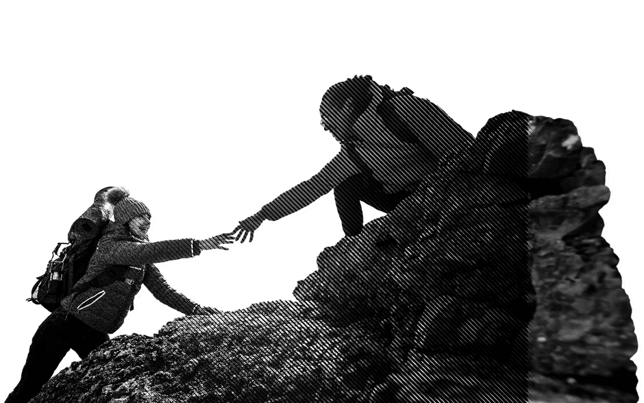 Two hikers, one helping another climb up a rock.